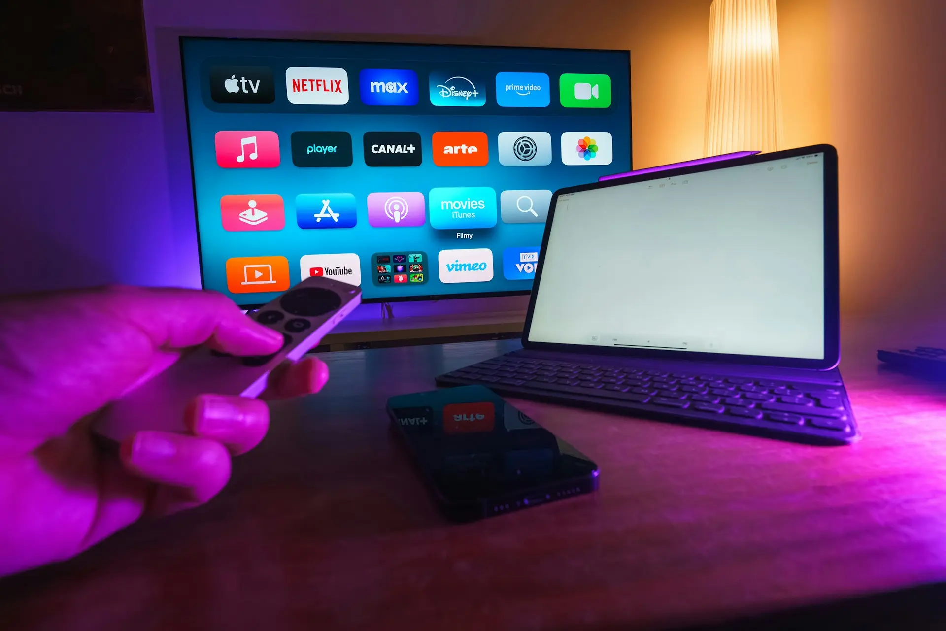 personne utilisant une télécommande face à un téléviseur affichant des applications de streaming