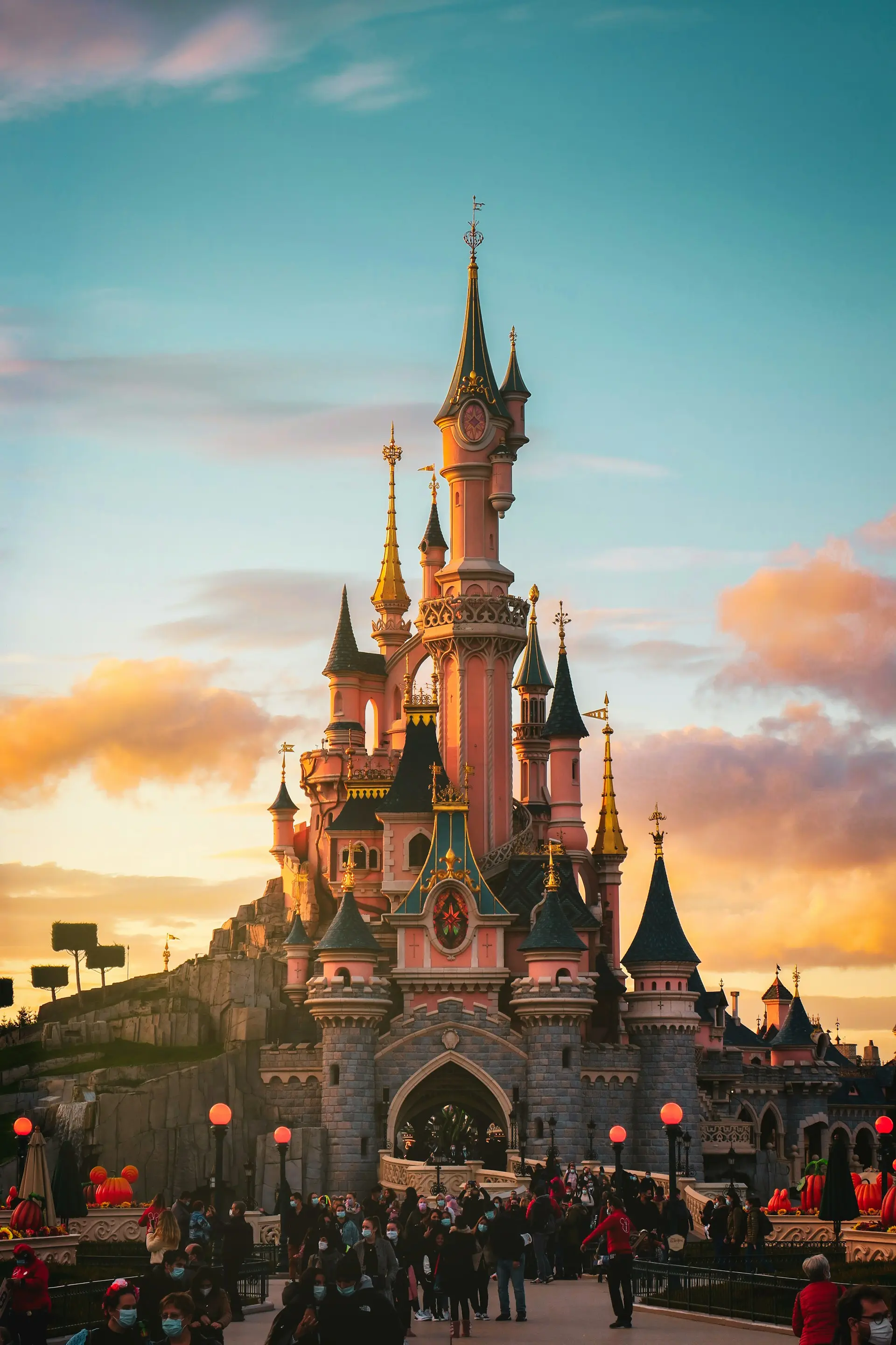 château de disney au coucher de soleil avec foule de visiteurs adultes et enfants