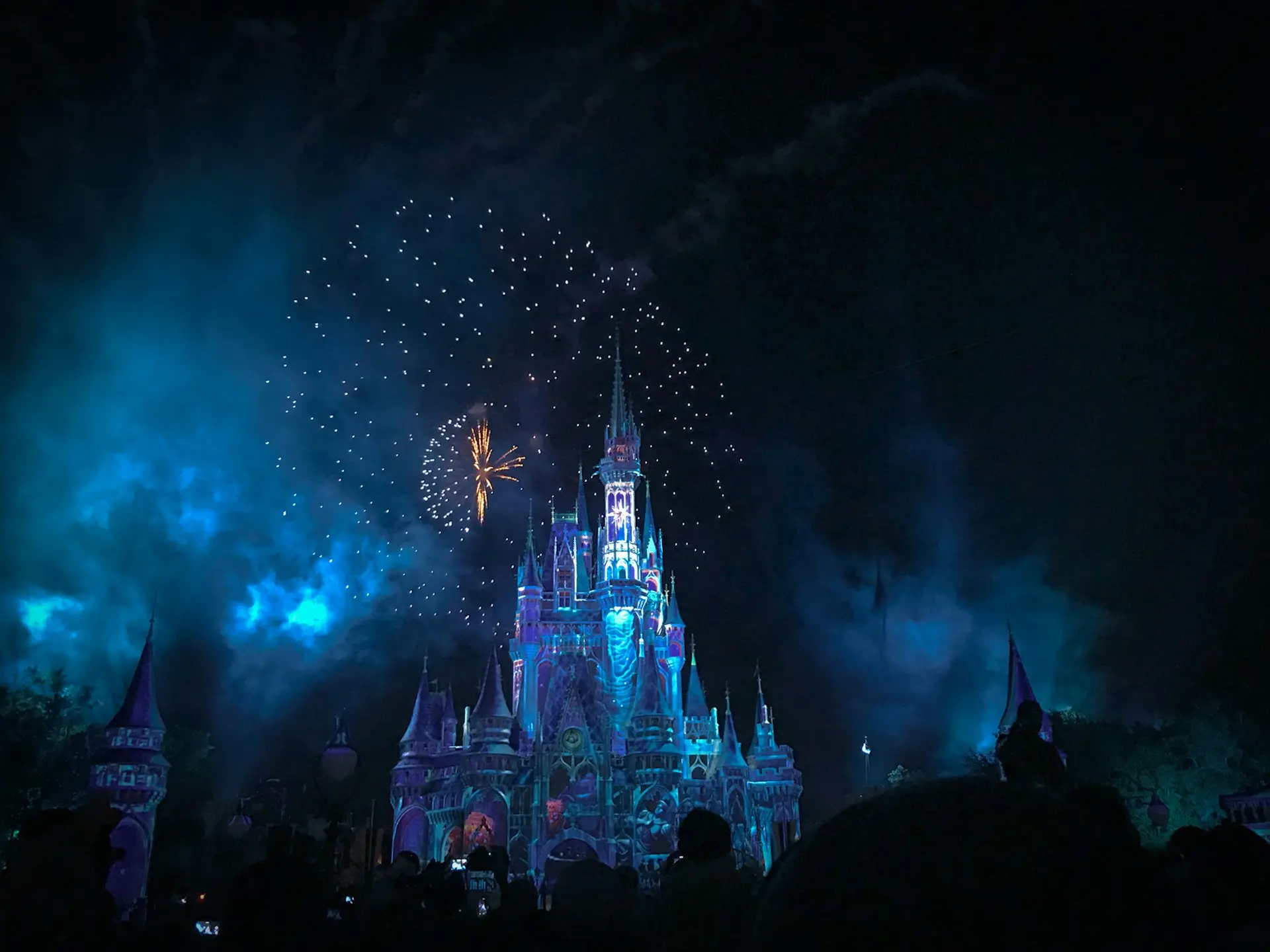 château disney illuminé la nuit avec feux d'artifice bleus et dorés